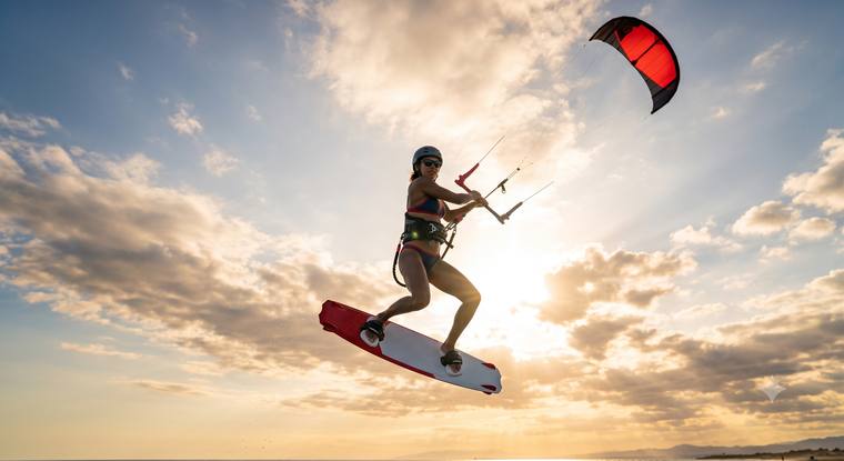 Kitesurferin springt im Gegenlicht bei Sonnenuntergang