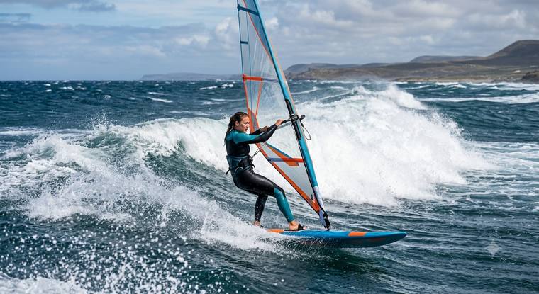 Windsurferin carvt vor rauer Küste